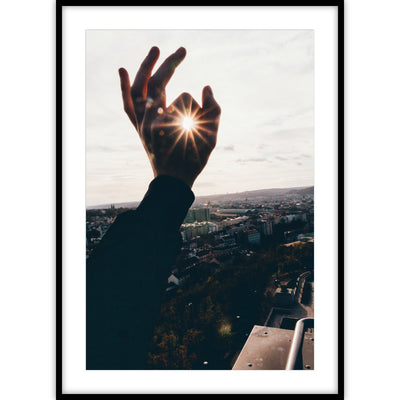 Ingelijste poster van een foto waarop de zon door een hand schijnt.