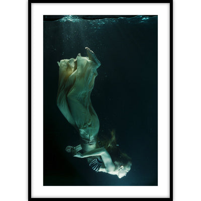 Ingelijste poster van vrouw die met kleding onderwater zwemt.