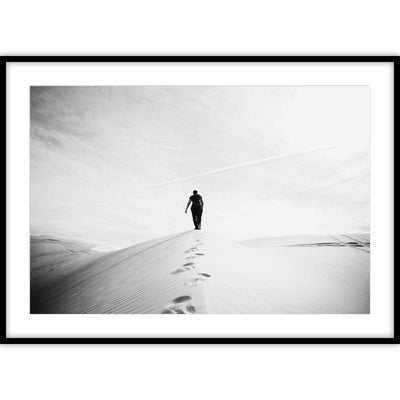 Ingelijste zwart-wit poster van een man die door de woestijn loopt.