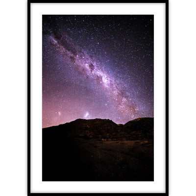 Een poster met een kleurenfoto van een paars/roze sterrenhemel boven donkerbruine bergen.