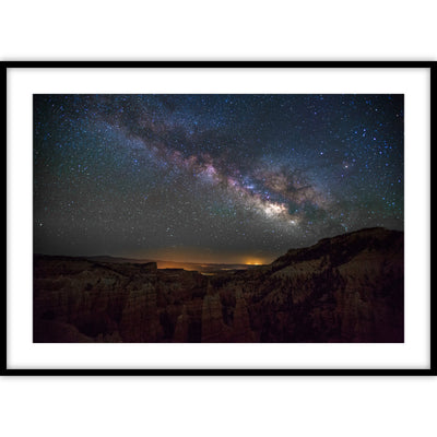 Een ingelijste poster met een foto van een ravijn met daarboven een sterrenhemel waarin de melkweg goed zichtbaar is.