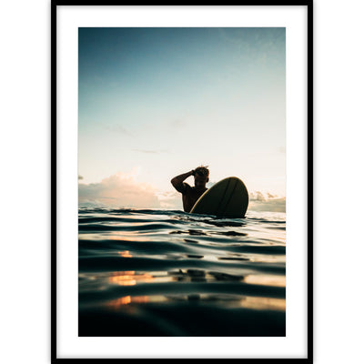 Een poster van een surfer met een surfboard genomen vanuit het water tijdens de zonsondergang.